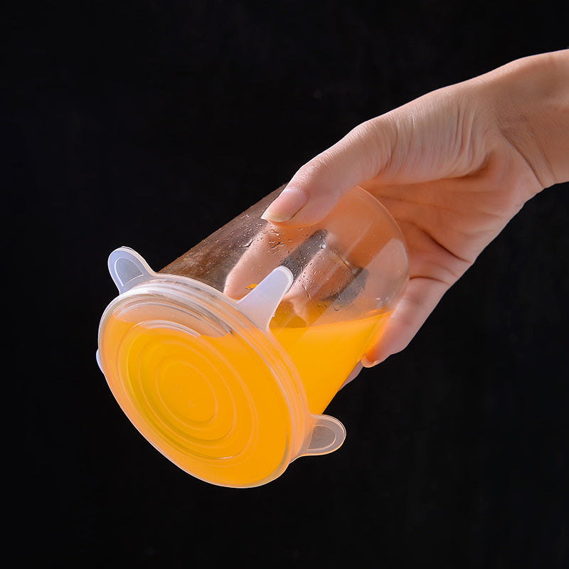 Hand holding a transparent container with a yellow lid against a black background