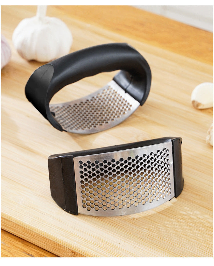 Garlic press on a wooden surface with garlic cloves around