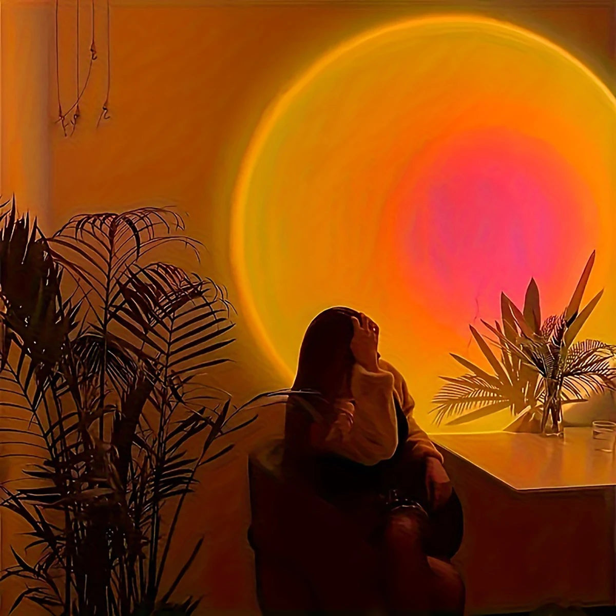 Person sitting in a room with a large circular light fixture casting a warm glow.