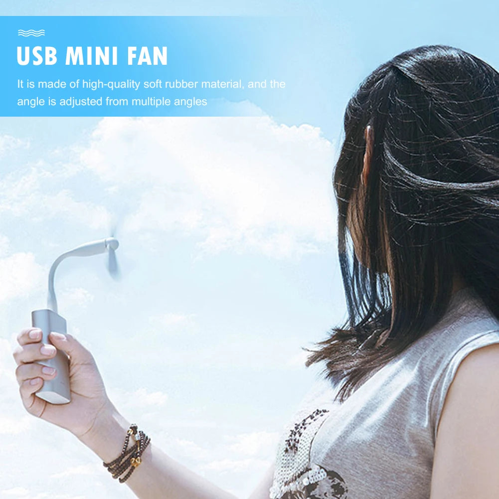 Person holding a USB mini fan with a blue sky background