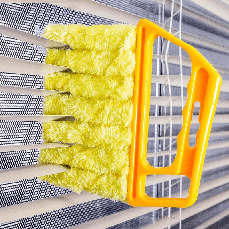Cleaning brush with yellow bristles and orange handle cleaning a metal surface