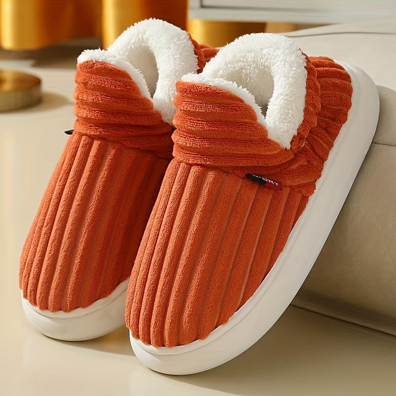 Pair of orange slippers with white fur lining on a light background