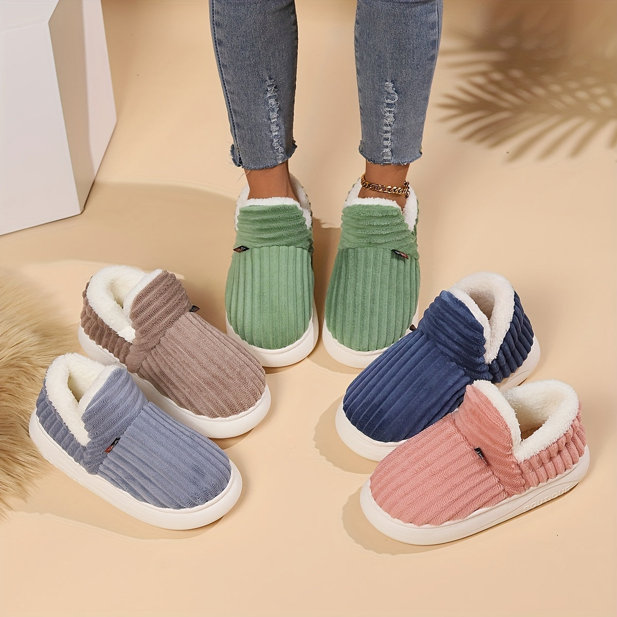 Four pairs of colorful slippers on a beige surface with a person wearing one pair.
