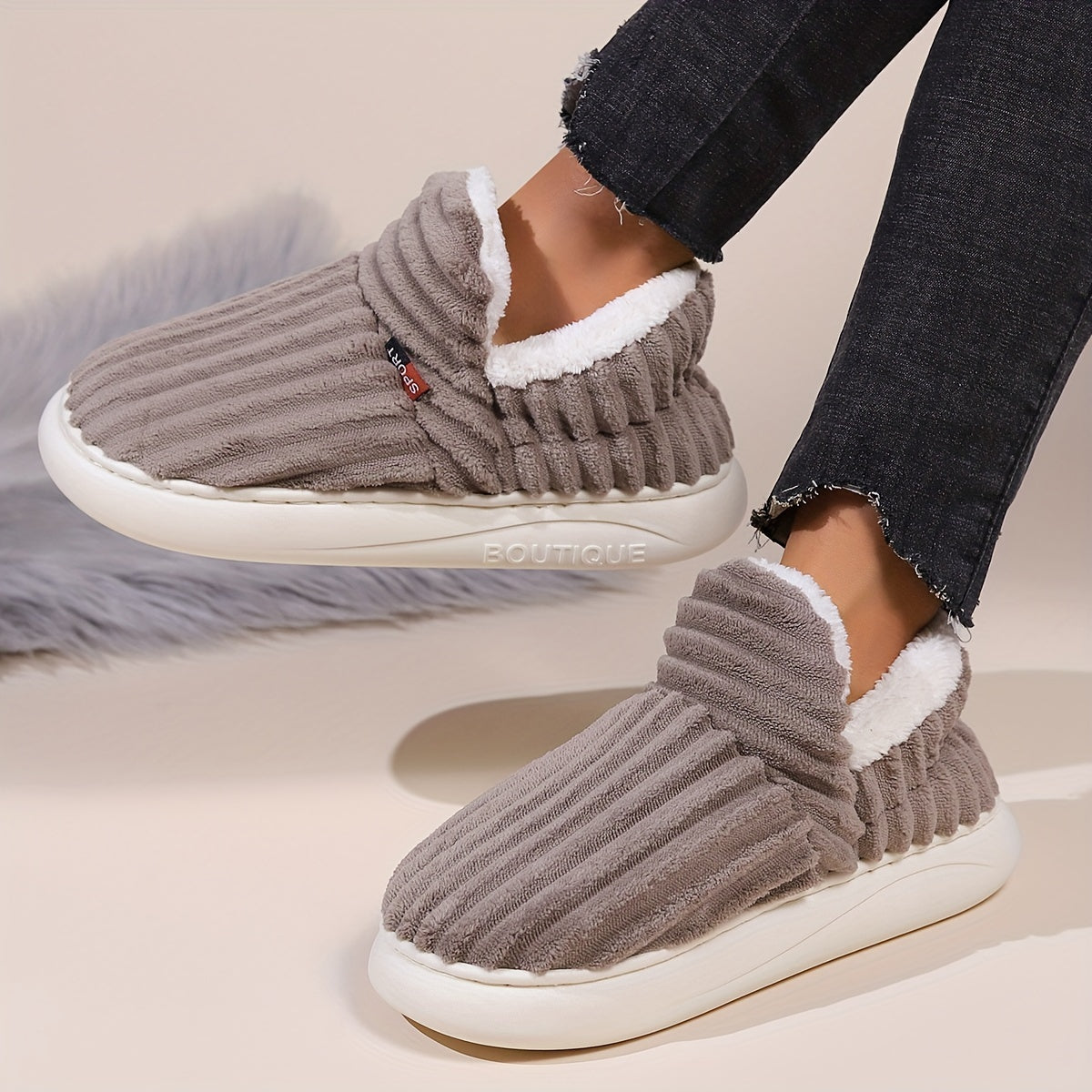 Gray slippers with white soles worn by a person on a light background
