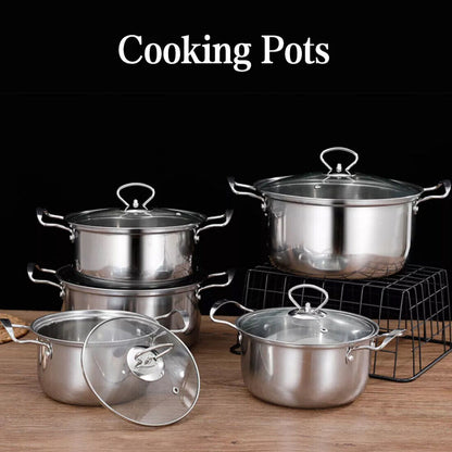 Set of stainless steel cooking pots with lids on a wooden surface.