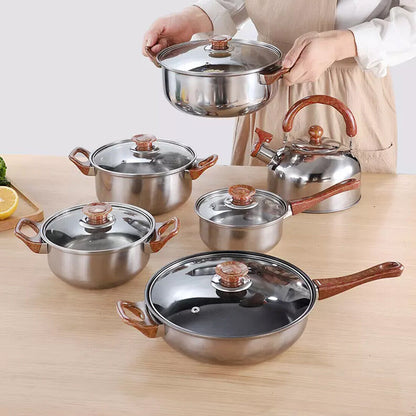 Set of stainless steel cookware with wooden handles on a wooden surface.