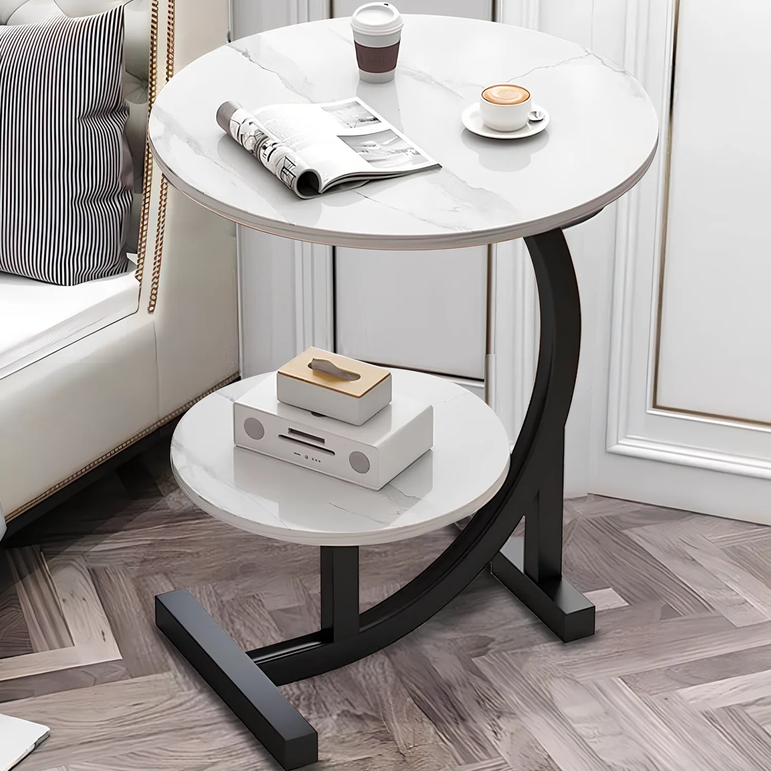 Round side table with marble top and black metal legs in a living room setting.
