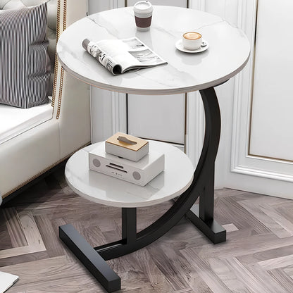 Round side table with marble top and black metal legs in a living room setting.
