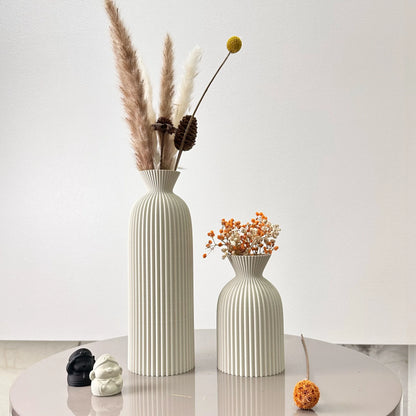 Two decorative vases with dried plants on a white surface