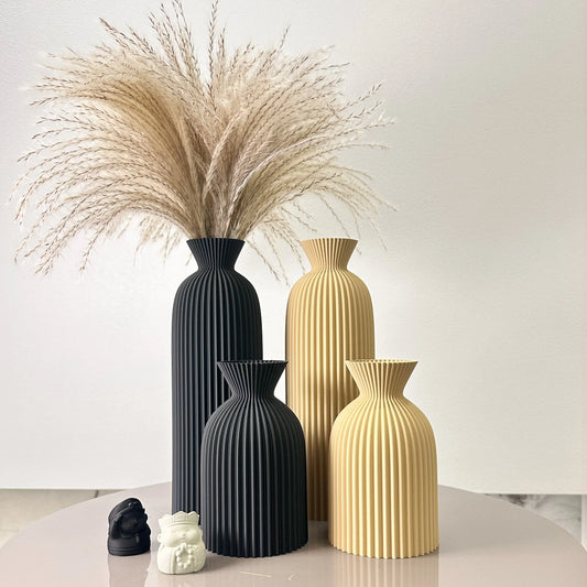 Set of black and gold vases with decorative elements on a light surface.
