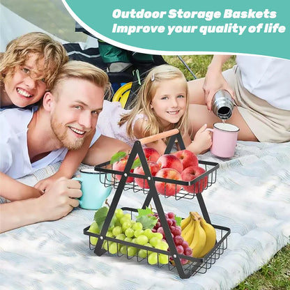 Family enjoying a picnic with a three-tiered fruit basket on a blanket outdoors.