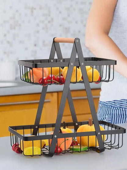 Two-tiered metal fruit basket with fruits on a kitchen counter