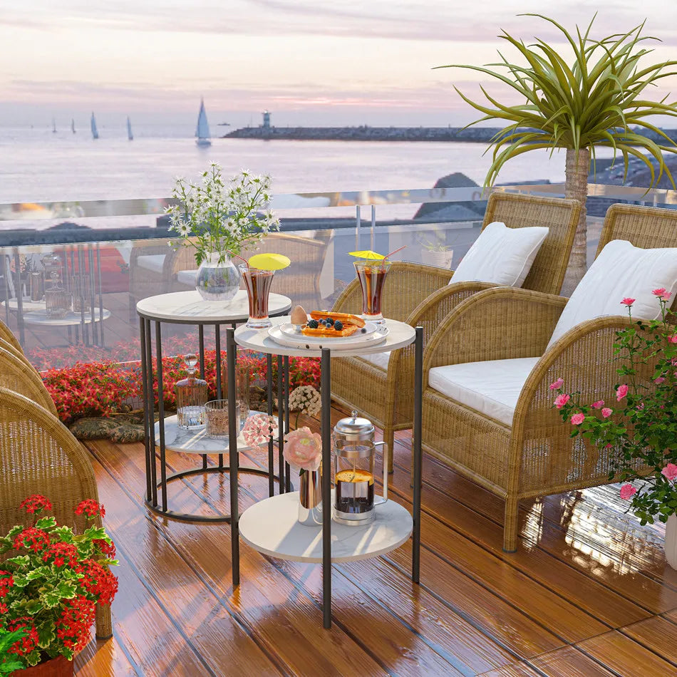 Outdoor seating area with wicker chairs, small tables, and decorative items on a wooden deck with a waterfront view.