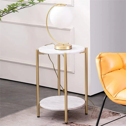 Small marble side table with gold legs and lamp in a modern living room.