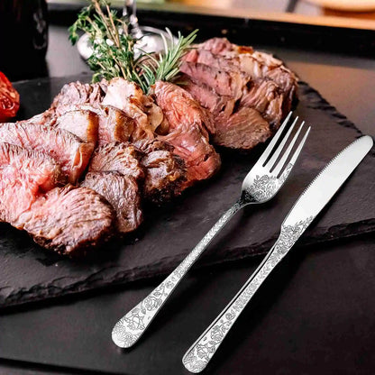 Sliced steak on a black slate with decorative silver fork and knife.