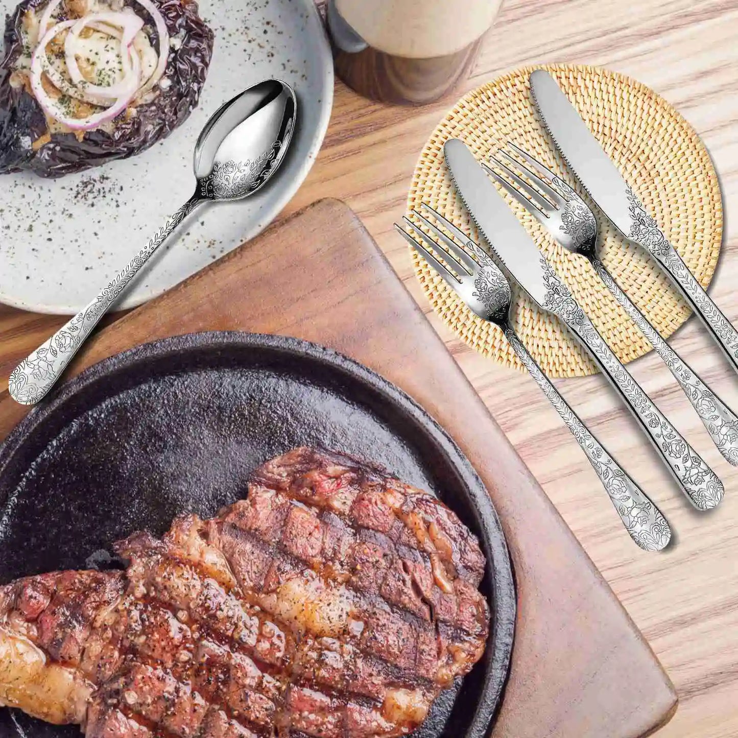Steak in a cast iron pan with silver cutlery on a wooden table