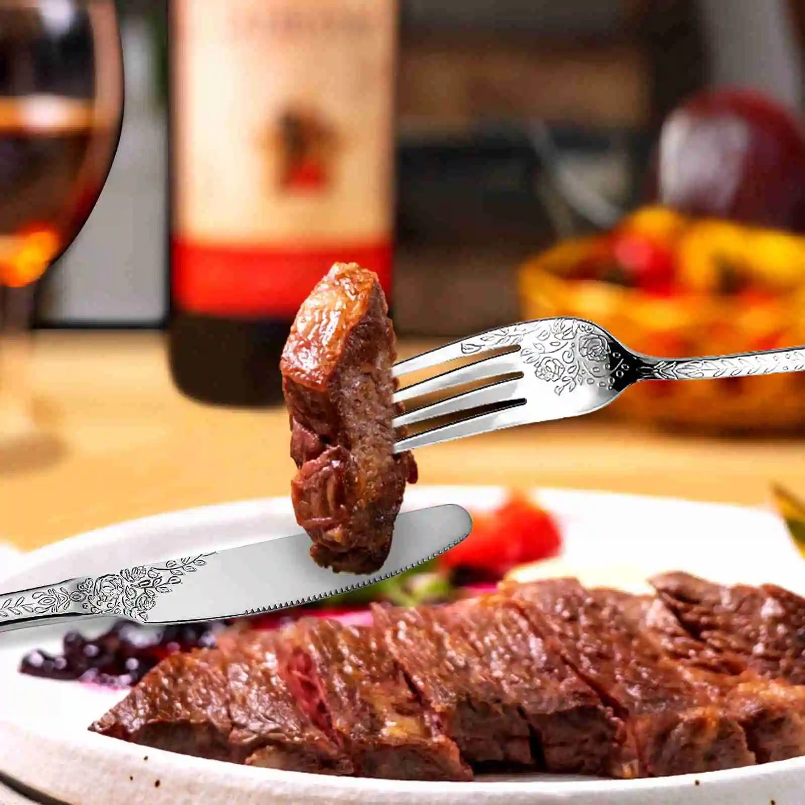 Steak on a fork with a knife, glass of red wine, and dessert in the background