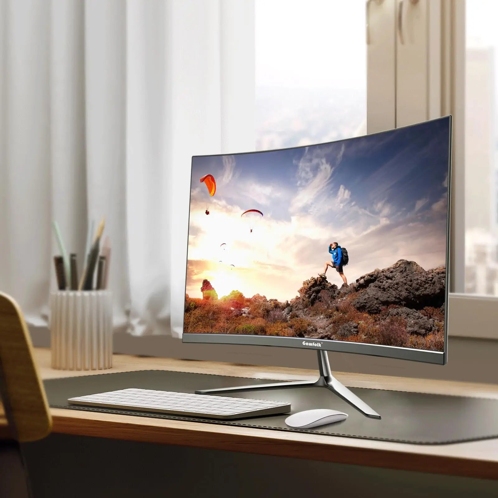 Computer monitor on a desk with a scenic wallpaper, keyboard, and mouse.