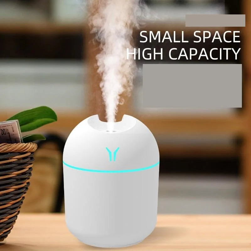 White humidifier with blue light on a wooden table, emitting steam.