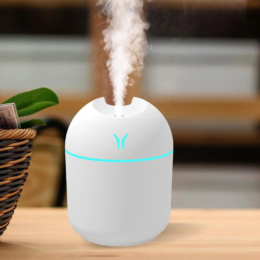 White humidifier with blue light on a wooden surface, emitting mist.