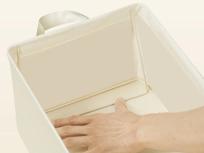 Hand opening a beige fabric storage box on a light beige background