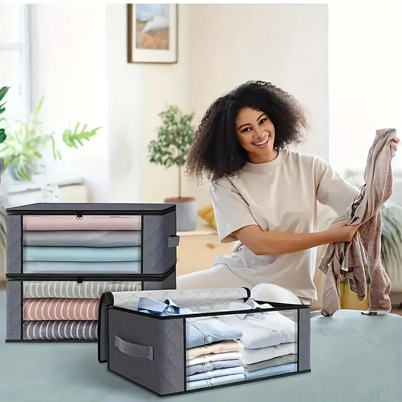 Woman organizing folded clothes in transparent storage boxes in a bright room.