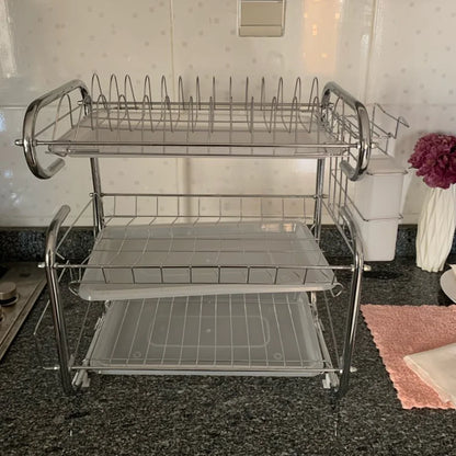 Three-tier metal dish rack on wheels in a kitchen setting.