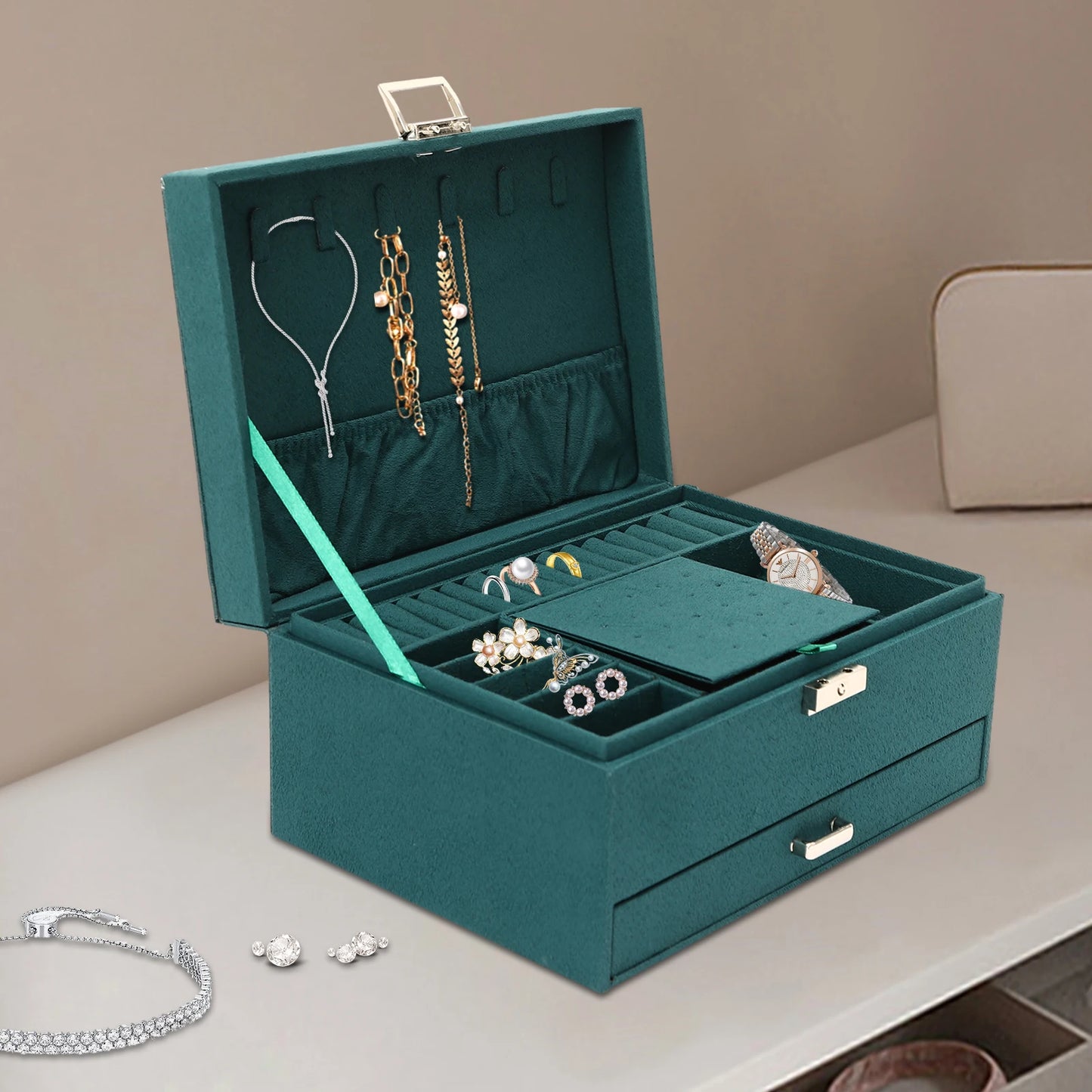 Teal jewelry box with jewelry on a beige surface