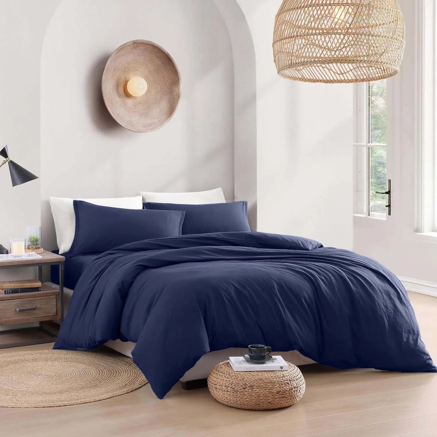Navy blue bedding set on a bed in a bedroom with wicker lampshades and decor.