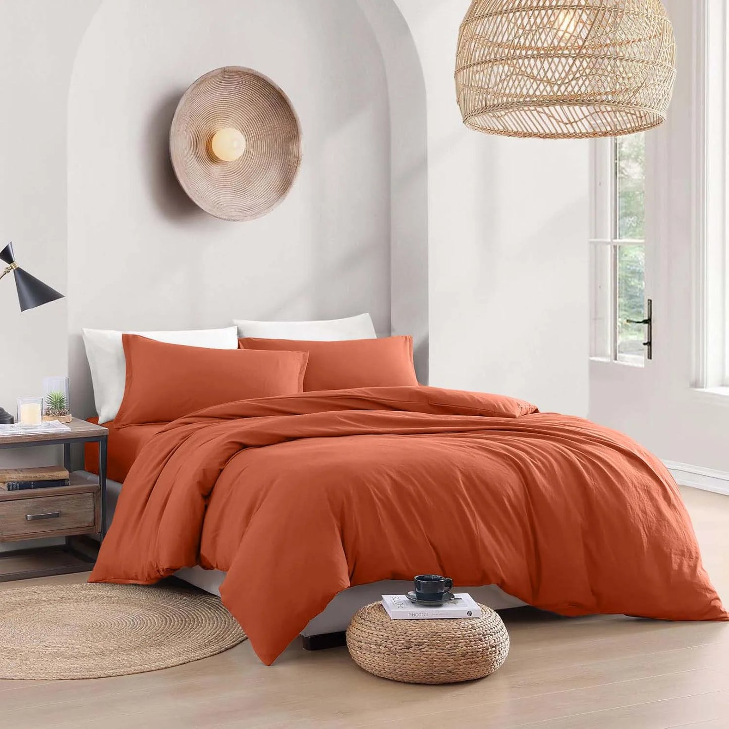 Orange bedding set on a bed in a bright bedroom with natural light.