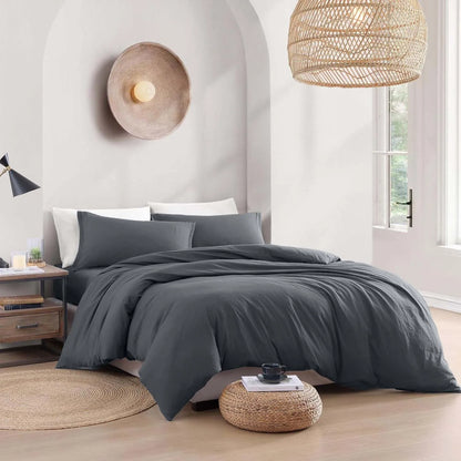 Gray bedding set on a bed in a modern bedroom with wooden floors and decorative lamps.