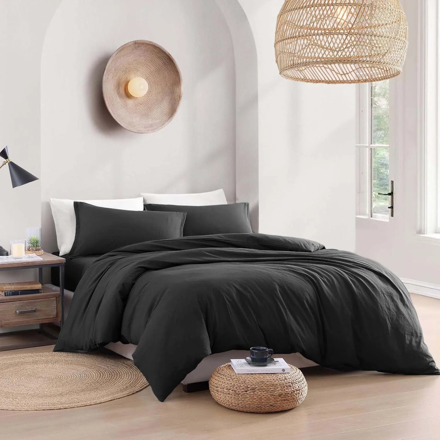 Black bedding set on a bed in a modern bedroom with wooden floors and decorative lamps.