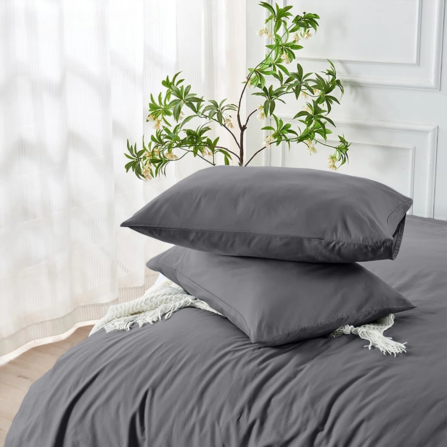 Gray bedding set with two pillows on a bed in a bedroom setting.