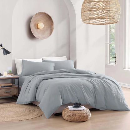 Gray bedding set on a bed in a bedroom with natural light and decor.