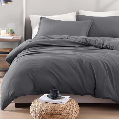 Gray bedding set on a bed in a bedroom with a side table and decor items.