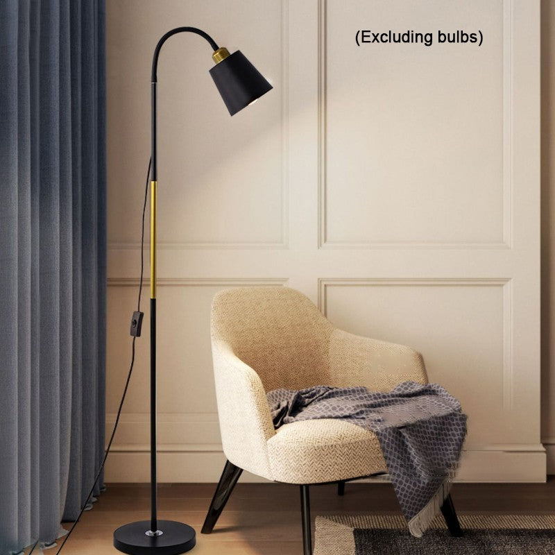 Floor lamp next to a chair with a blanket in a room setting