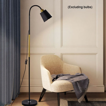 Floor lamp next to a chair with a blanket in a room setting