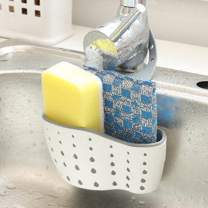 Kitchen sink caddy holding a sponge and scrubber next to a faucet.