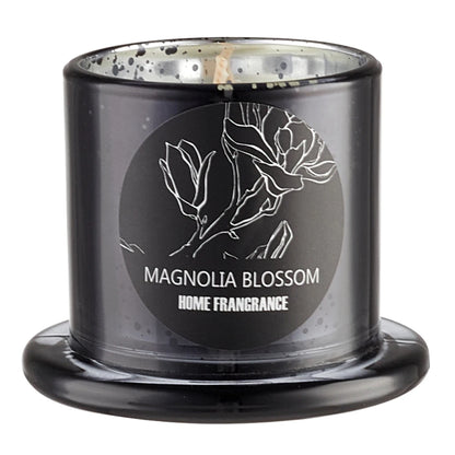 Black candle with 'Magnolia Blossom Home Fragrance' label on a white background