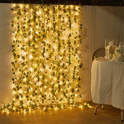 Decorative string lights with green leaves on a wall next to a table with a white tablecloth.