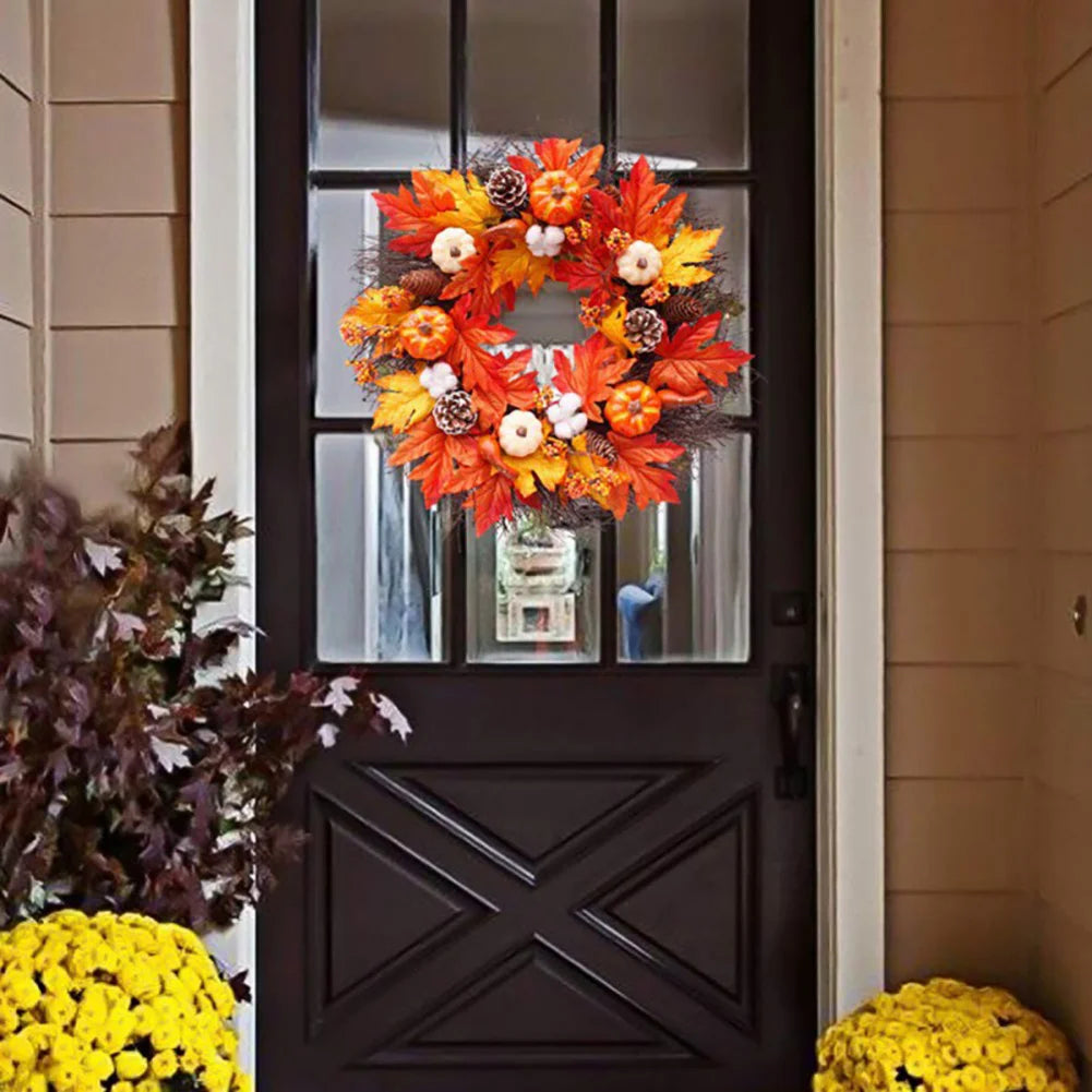 Decorative wreath with autumn leaves and pumpkins on a black door.