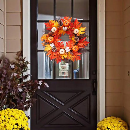 Decorative wreath with autumn leaves and pumpkins on a black door.