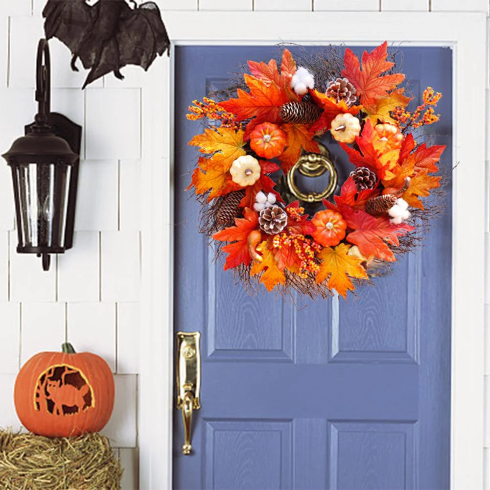 Decorative wreath with pumpkins and leaves on a blue door, with a bat and lantern in the background.