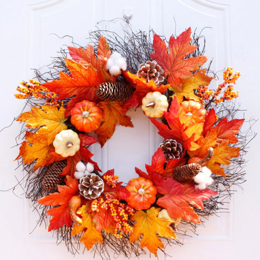 Autumn wreath with leaves, pumpkins, and pinecones on a white door.