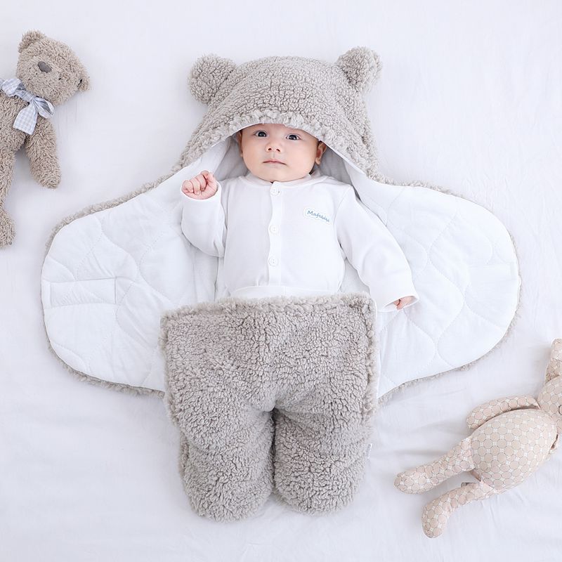 Baby in a white outfit with gray fleece legs and ears, surrounded by teddy bears on a light background