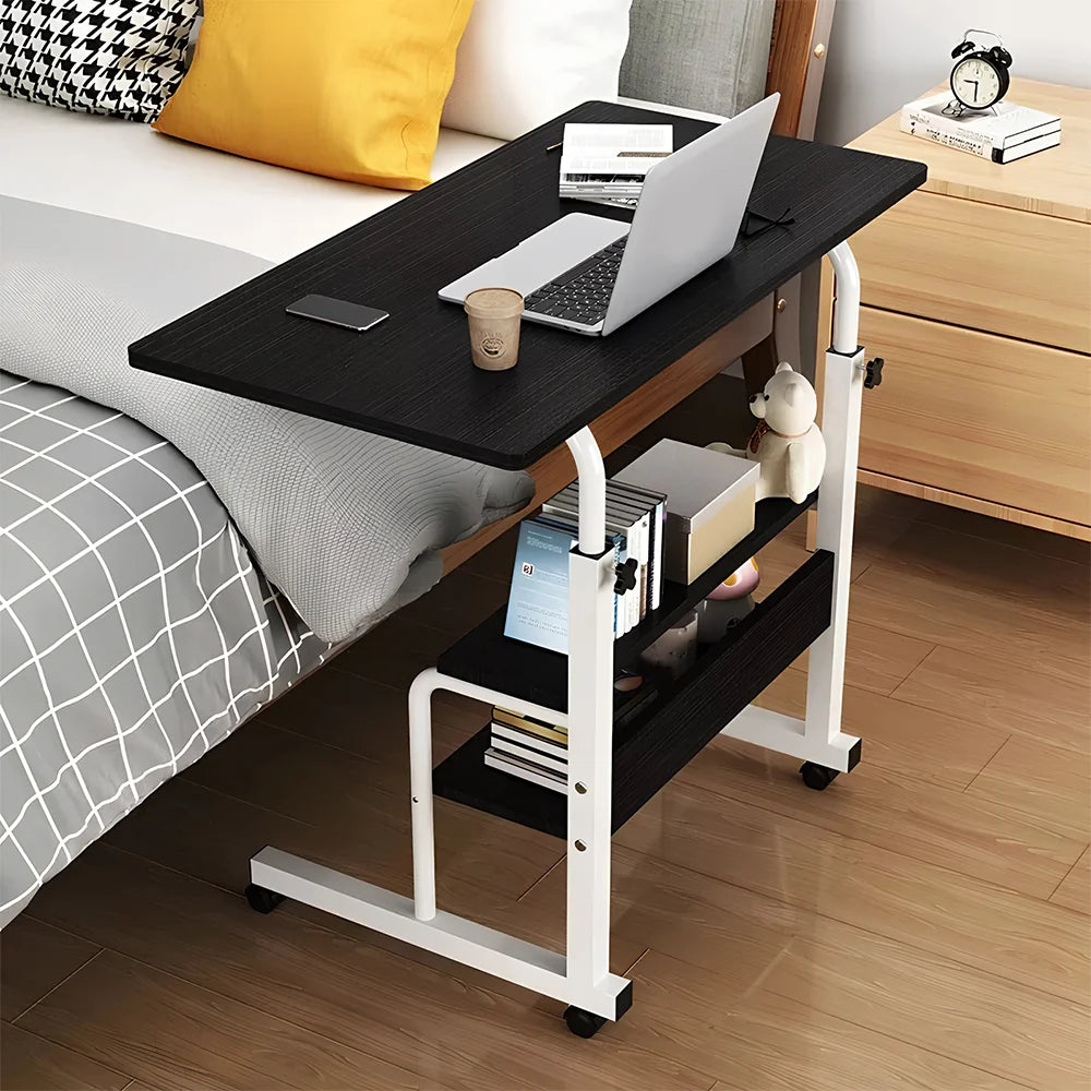 Adjustable bed side table with laptop, phone, and cup on a wooden floor.