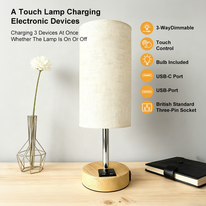 Table lamp with charging ports on a wooden surface, featuring a vase and notebook.