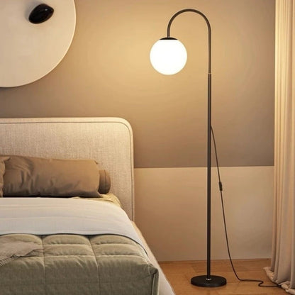 Floor lamp with a round white light bulb in a bedroom setting.