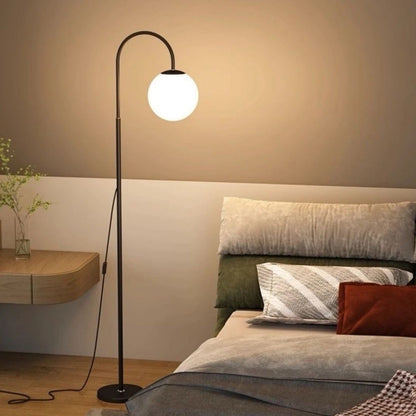 Modern bedroom with a floor lamp, bed, and side table.