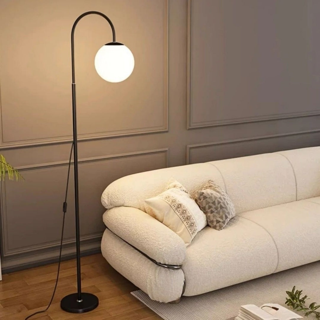 Modern living room with a white sofa, decorative pillows, and a floor lamp.